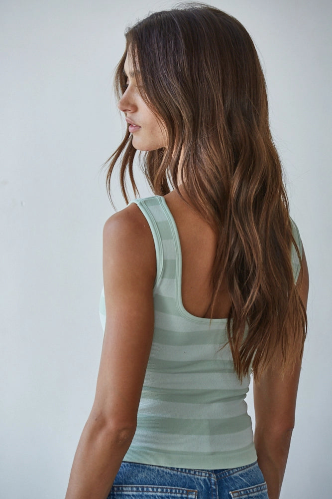Woman wearing a light green tank top against a plain background