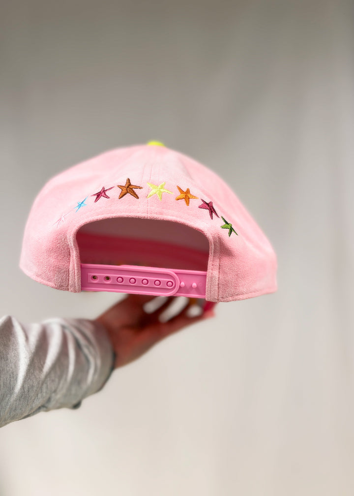 Back of trucker hat showing embroidered stars on pink faux suede hat on plain background