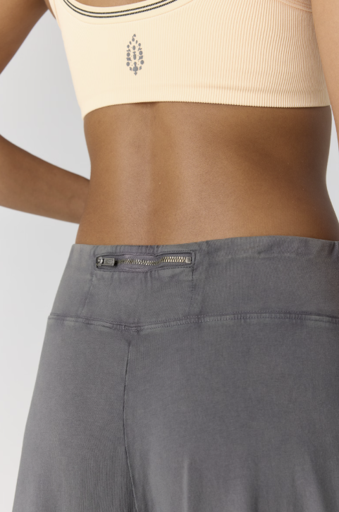 Close up of grey pants with zipper detail and yellow bra with logo on plain background