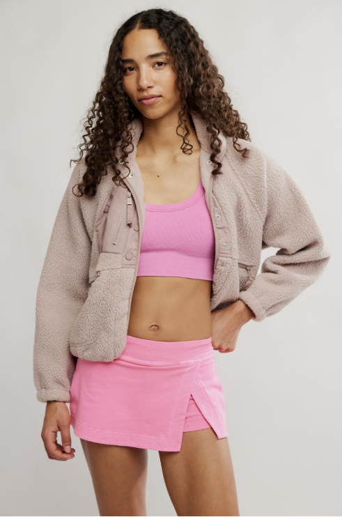 Woman wearing hot pink skort and bra on white background