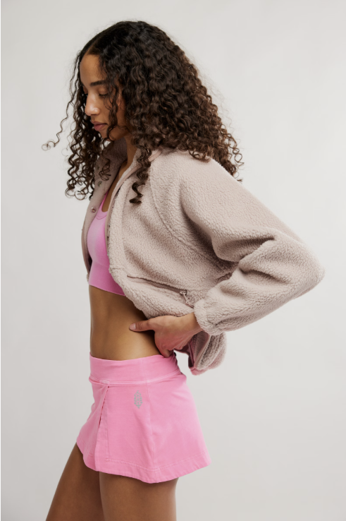 Woman wearing hot pink skort and bra on white background