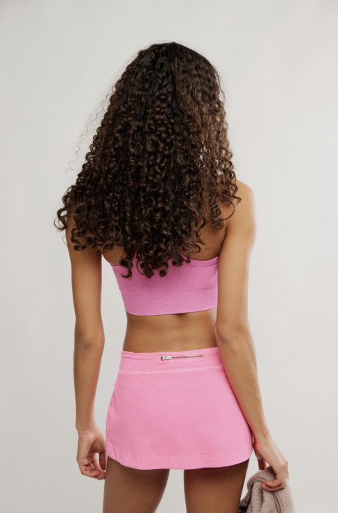 Woman wearing hot pink mini skort and bra on white background