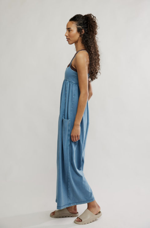 Woman wearing a blue onesie standing against a plain background