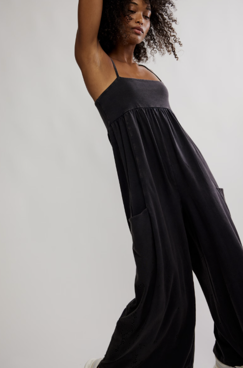 Woman wearing a black jumpsuit against a plain background