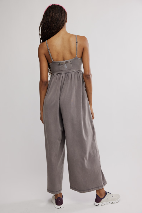 Person wearing a gray jumpsuit on a plain background
