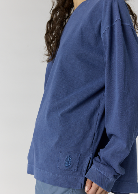 Woman wearing oversize blue long sleeve top on plain background