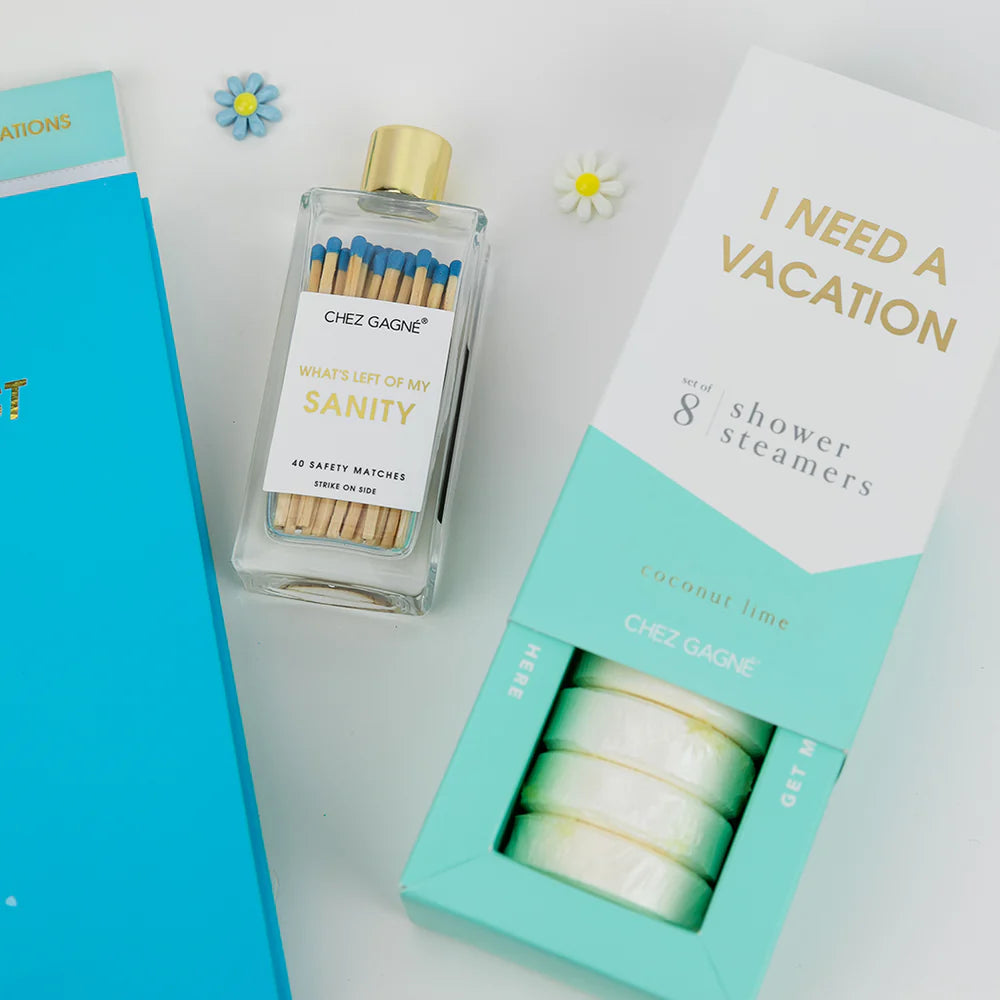 Chez Gagnie shower steamers set featuring a clear glass bottle with a gold cap and safety match bottle, alongside its turquoise and white packaging box labeled &