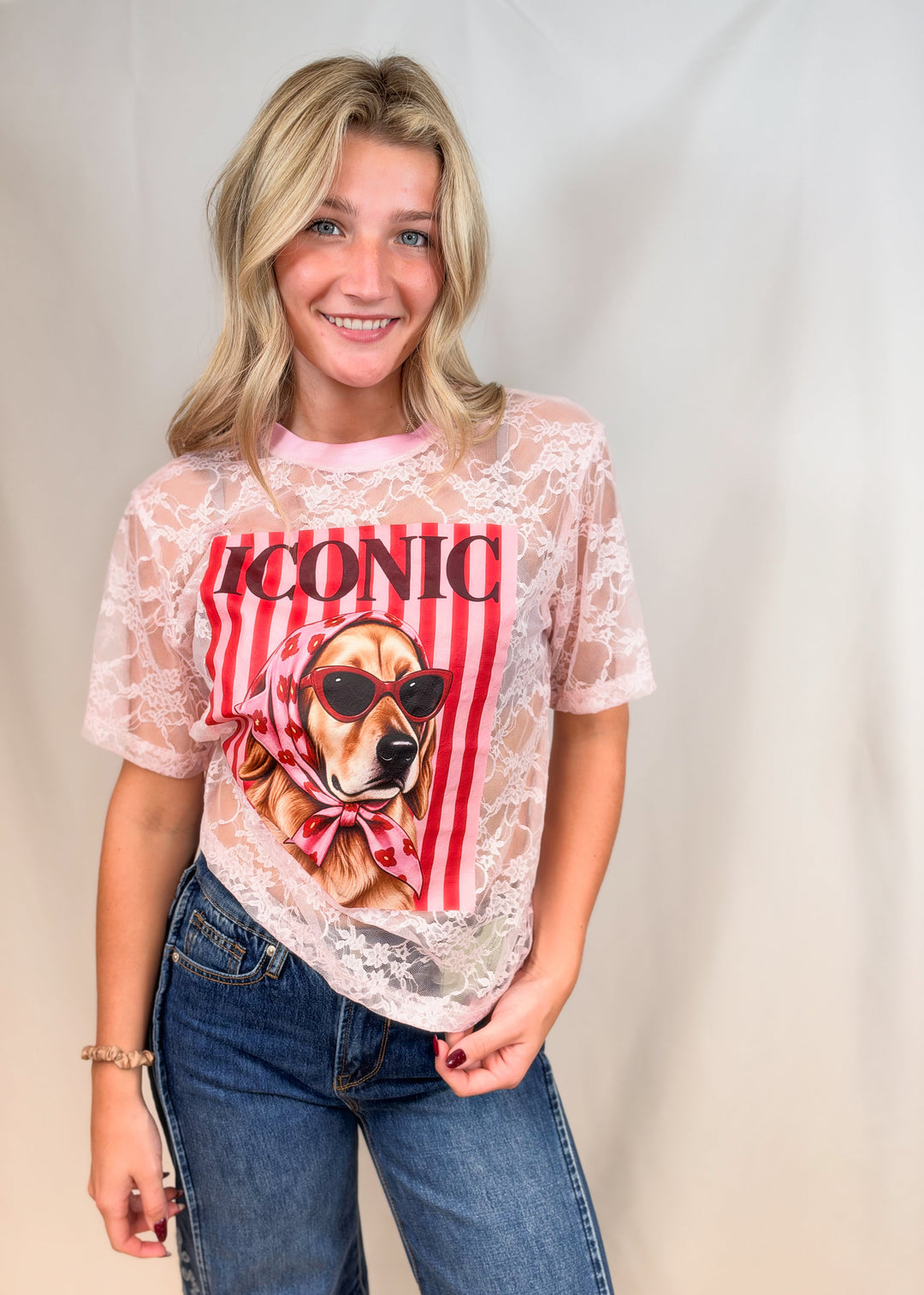 Woman wearing pink lace tee with golden retriever graphic on front on plain background