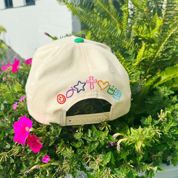 Beige cap with colorful symbols on a plant with flowers