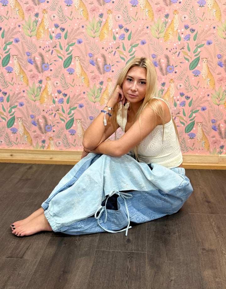 Woman sitting on the floor against a colorful wall with floral and animal patterns.