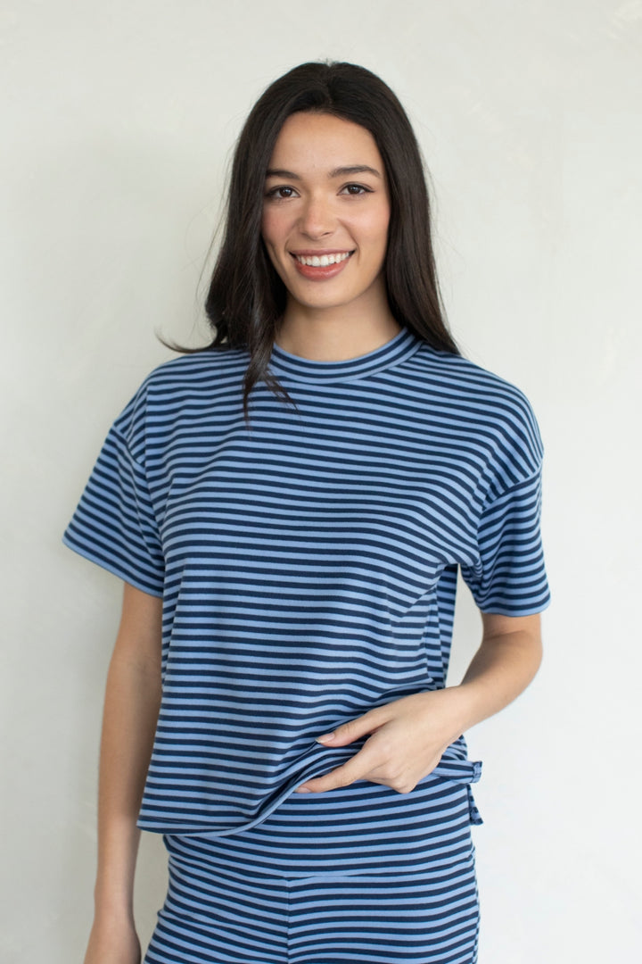 Woman wearing navy and blue stripe top and pants on plain background