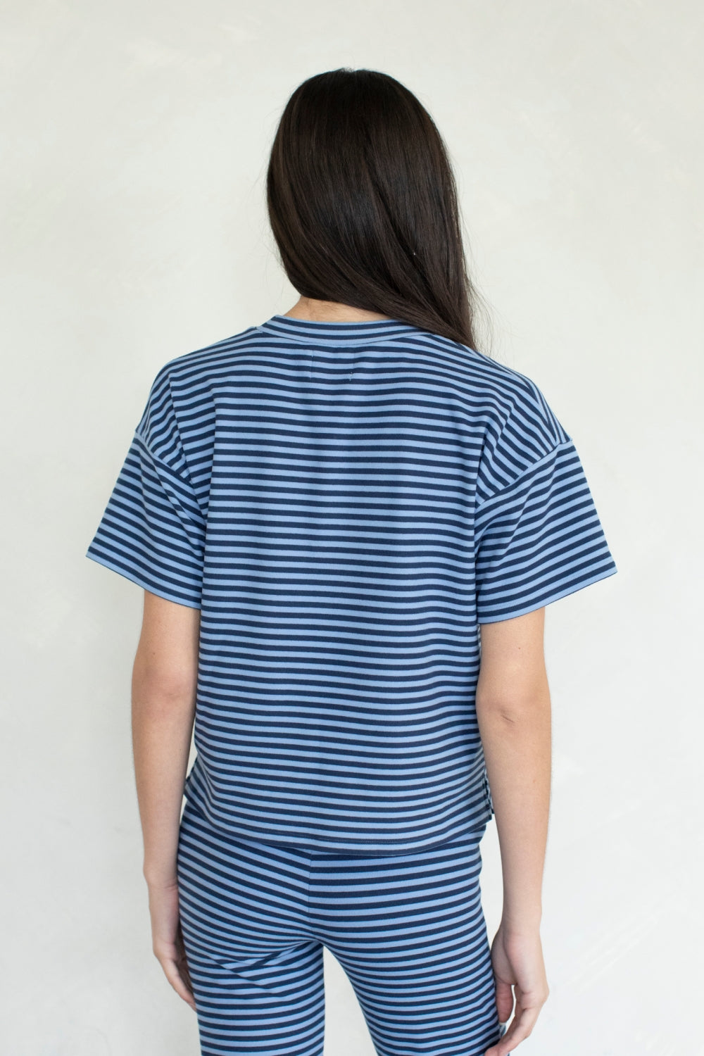 Person wearing a blue and white striped outfit against a plain background