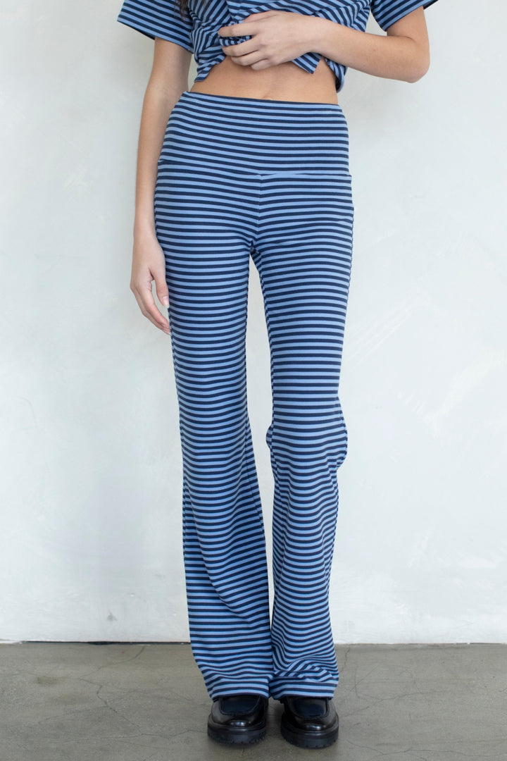 A person wearing blue and white horizontally striped high-waisted flare pants with a matching striped cropped top, standing against a plain light wall.