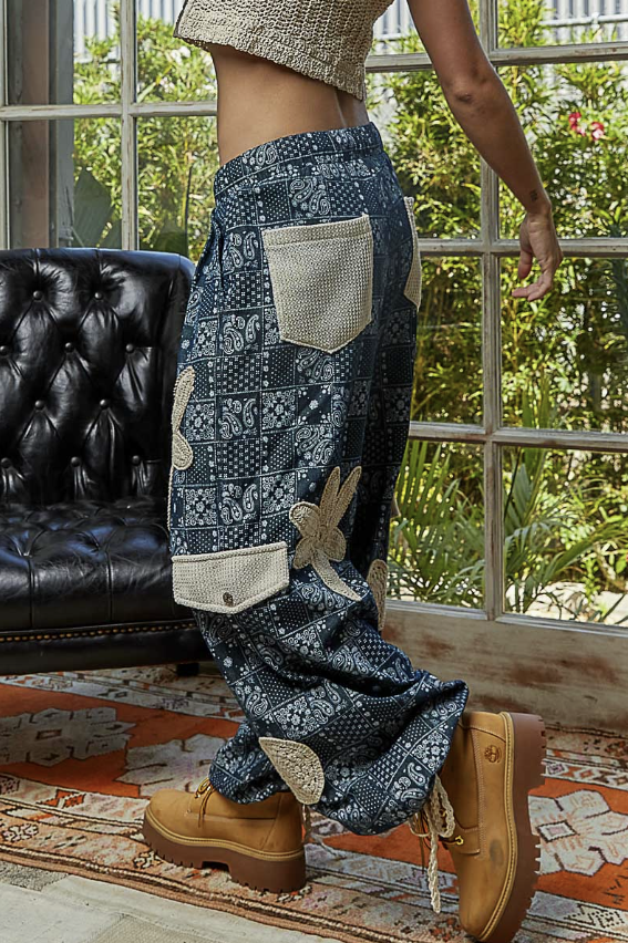 Person wearing patterned pants and brown boots indoors with a window and chair in the background