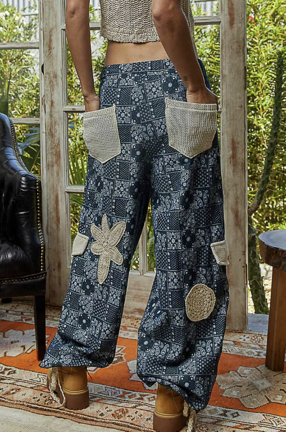 Person wearing blue patterned pants with beige accents in a room with plants and furniture.