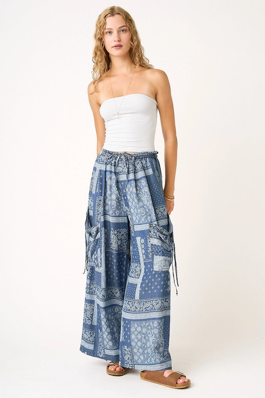 Woman wearing a strapless white top and blue patterned skirt on a white background