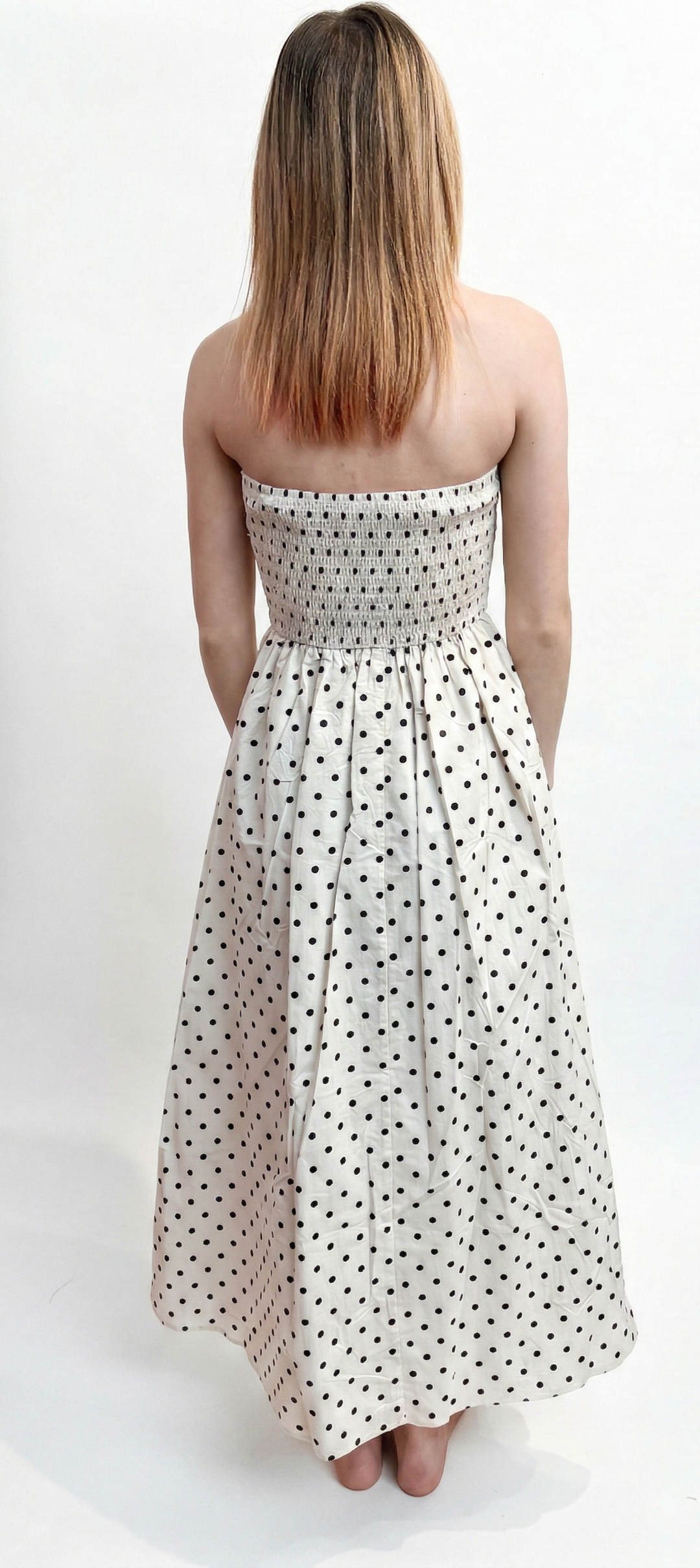 Woman wearing a strapless polka dot dress on a white background