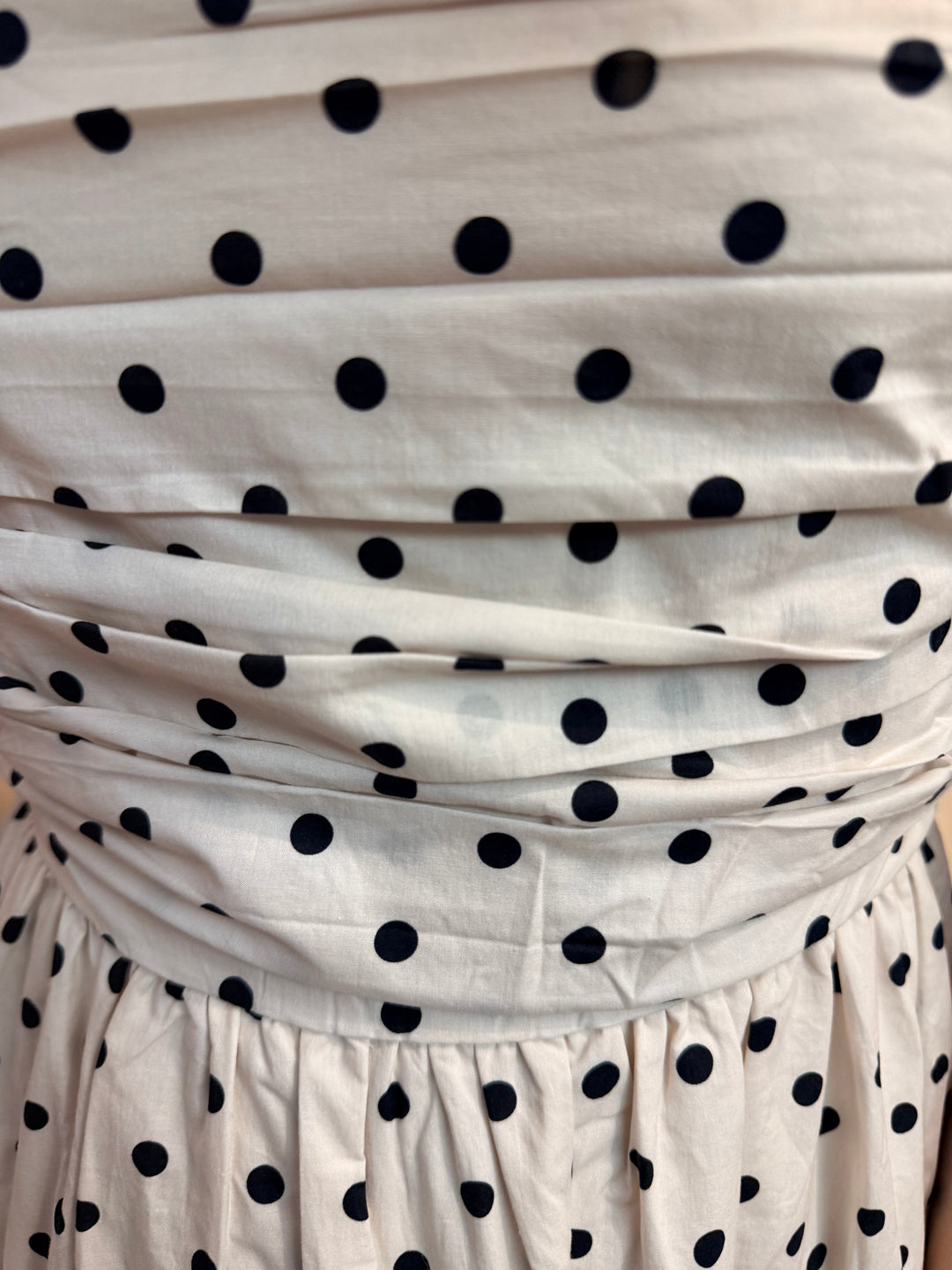 White fabric with black polka dots, possibly a curtain or scarf.
