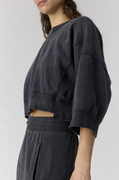 Person wearing a dark gray sweatshirt and pants on a white background