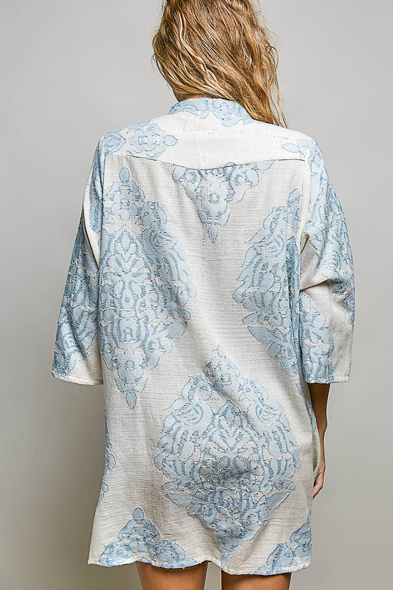 Back of woman wearing embroidered dress on plain background