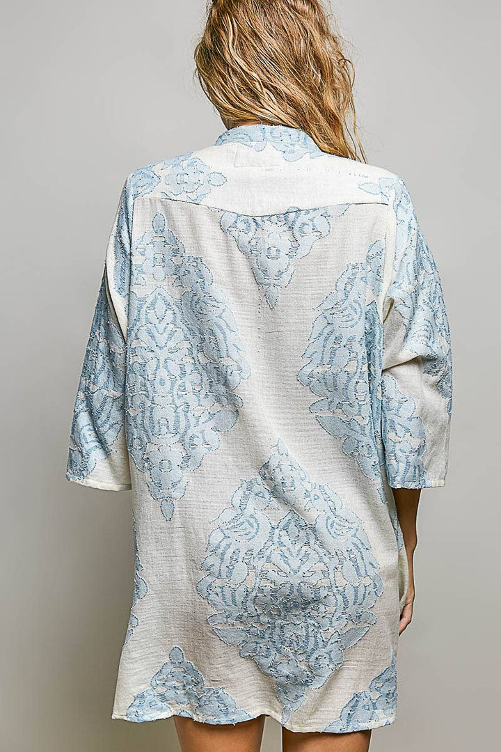 Back of woman wearing embroidered dress on plain background