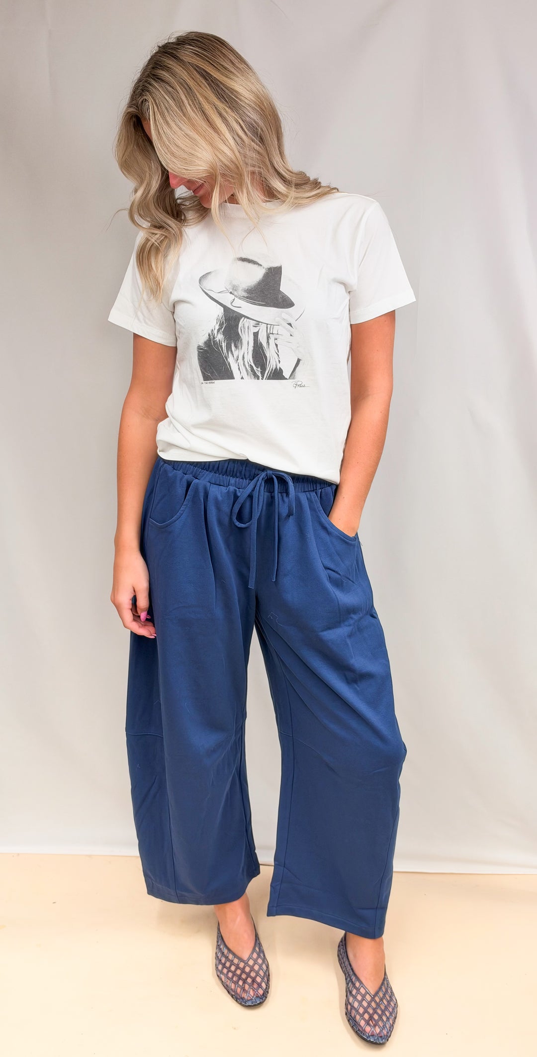 Woman wearing blue barrel sweatpants with graphic tee on plain background