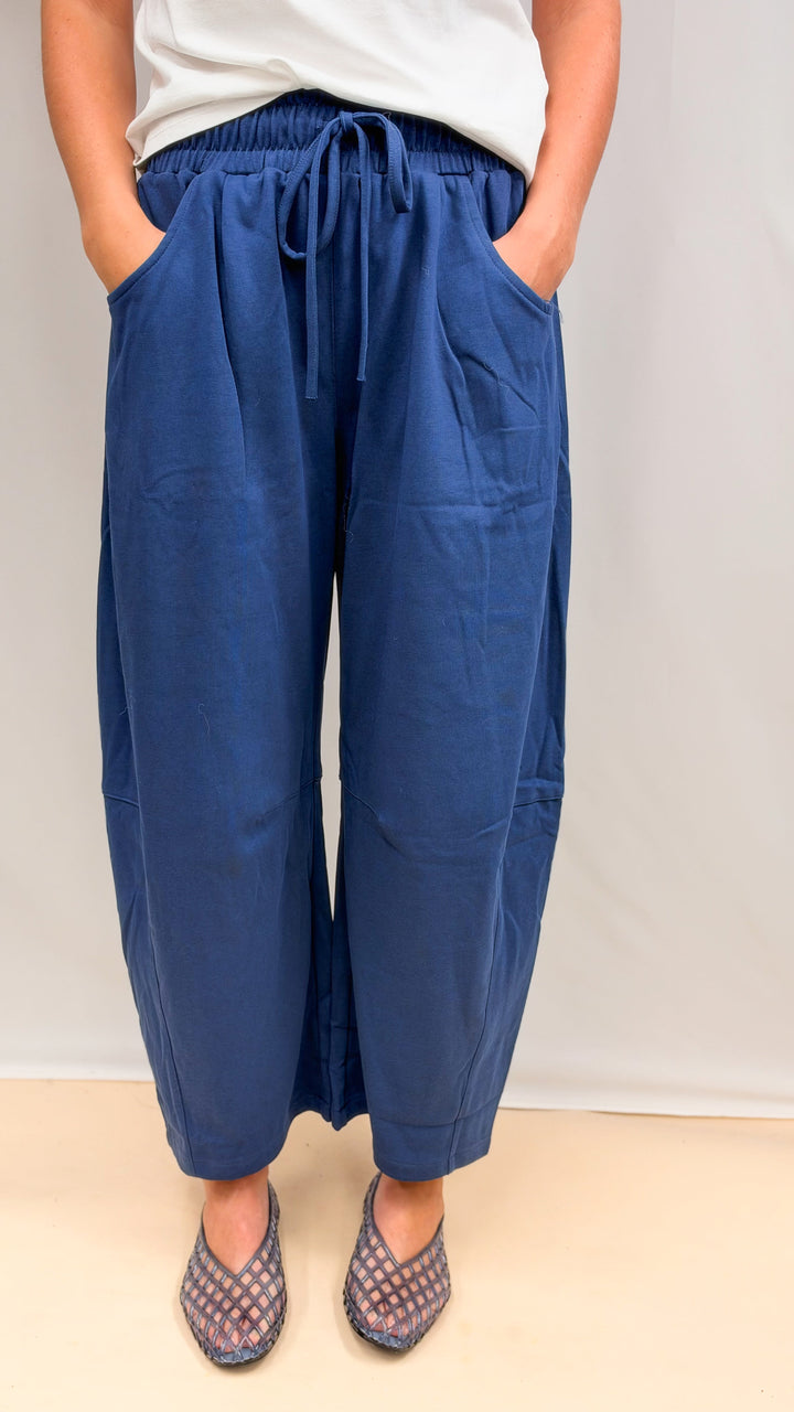 Woman wearing blue barrel sweatpants on plain background