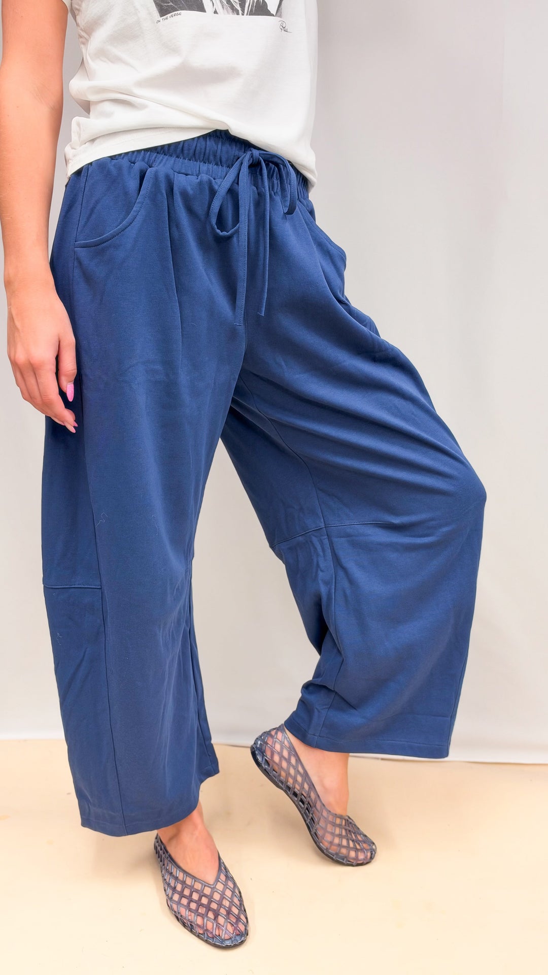Woman wearing blue barrel sweatpants with graphic tee on plain background