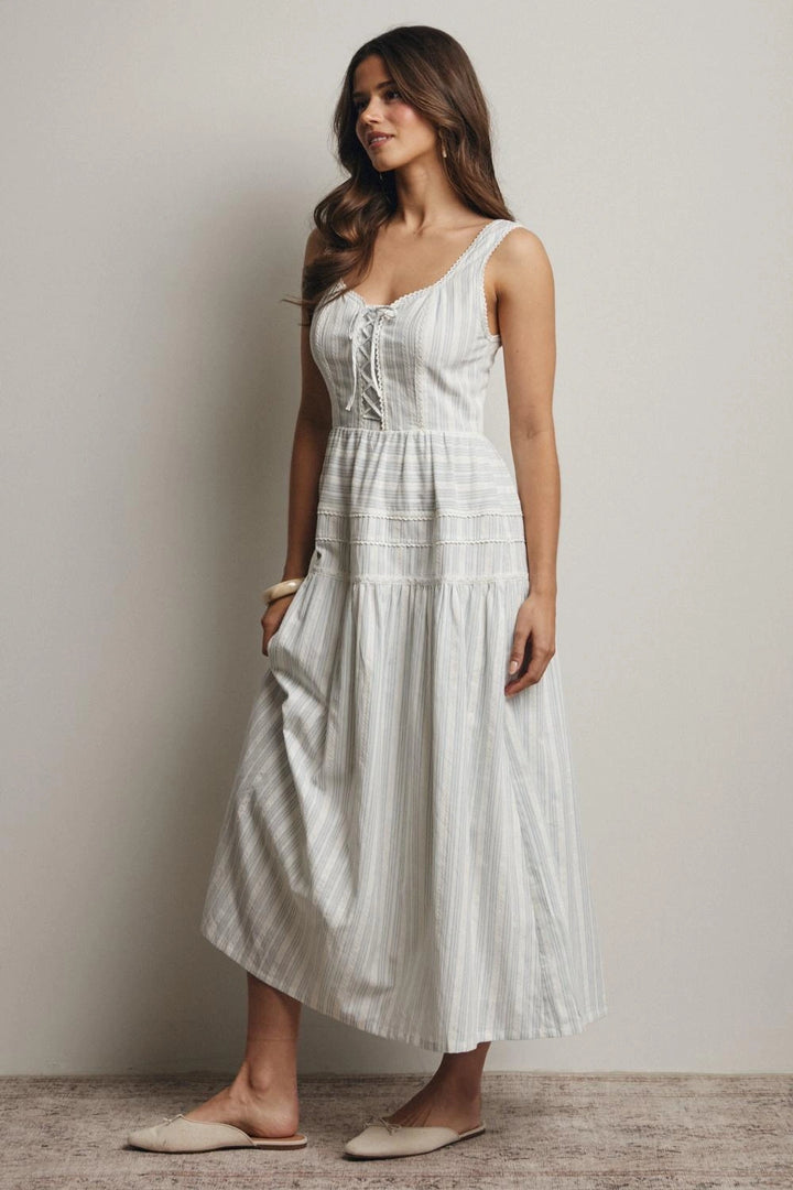 Woman wearing a white dress standing against a plain background