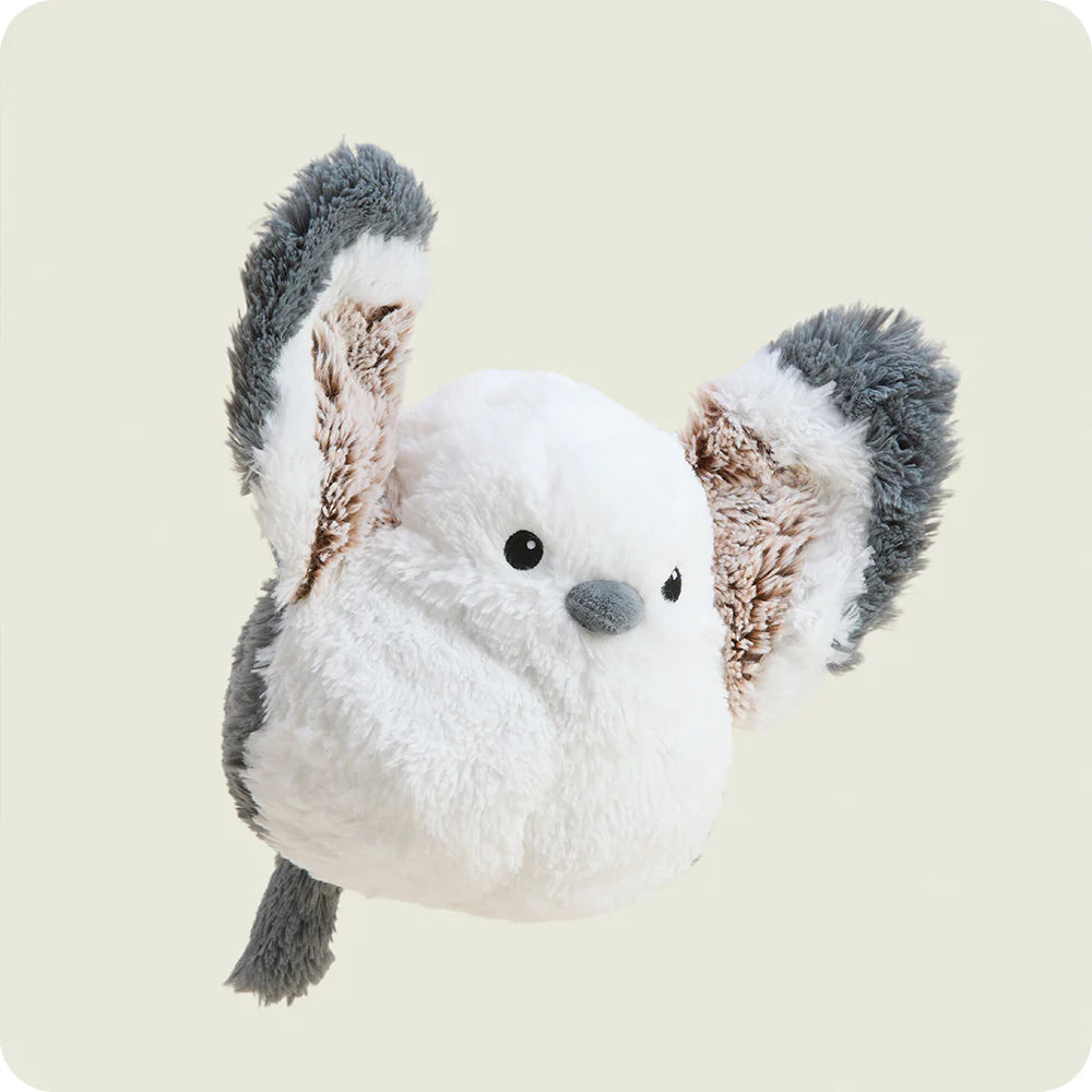 Plush toy owl with gray and brown feathers on a beige background