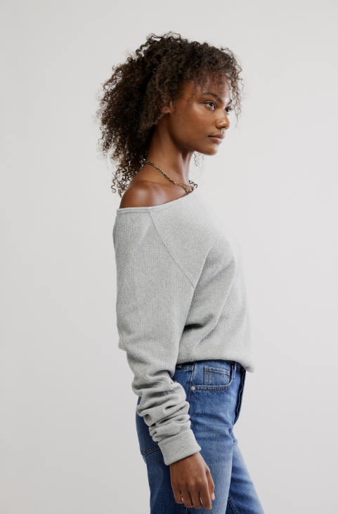 Woman wearing grey long sleeve and jeans on white background