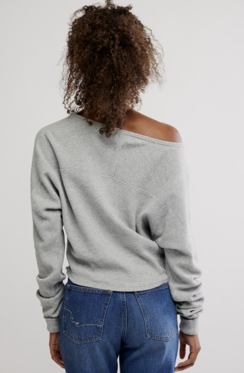 Woman wearing grey long sleeve and jeans on white background
