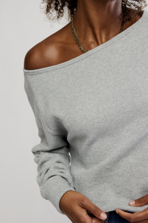 Woman wearing grey long sleeve top on white background