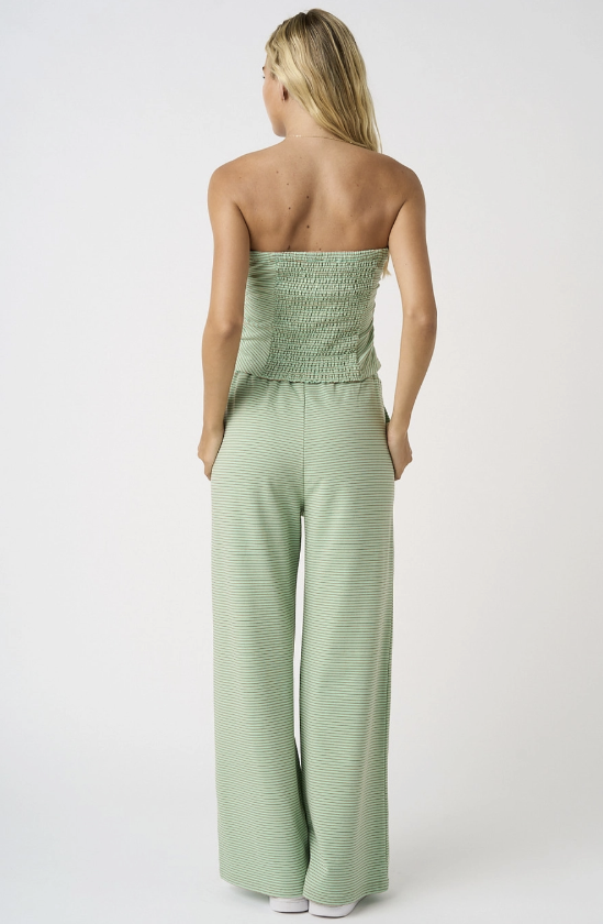 Woman wearing a strapless green jumpsuit on a white background