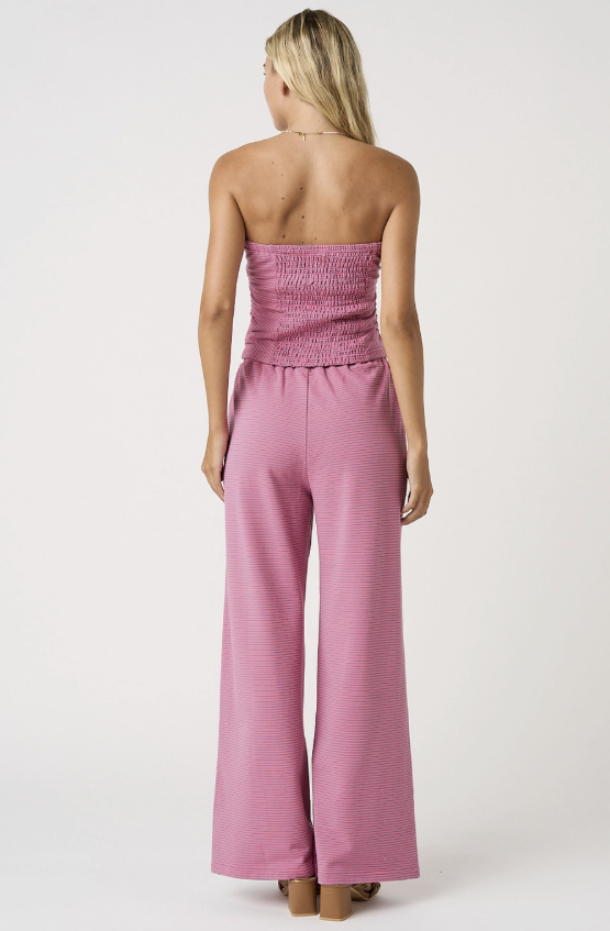 Woman wearing a pink strapless jumpsuit on a white background