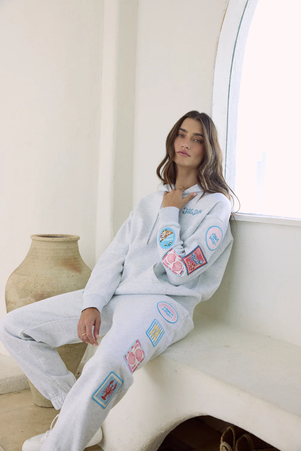 woman wearing grey hoodie with patches sitting on couch