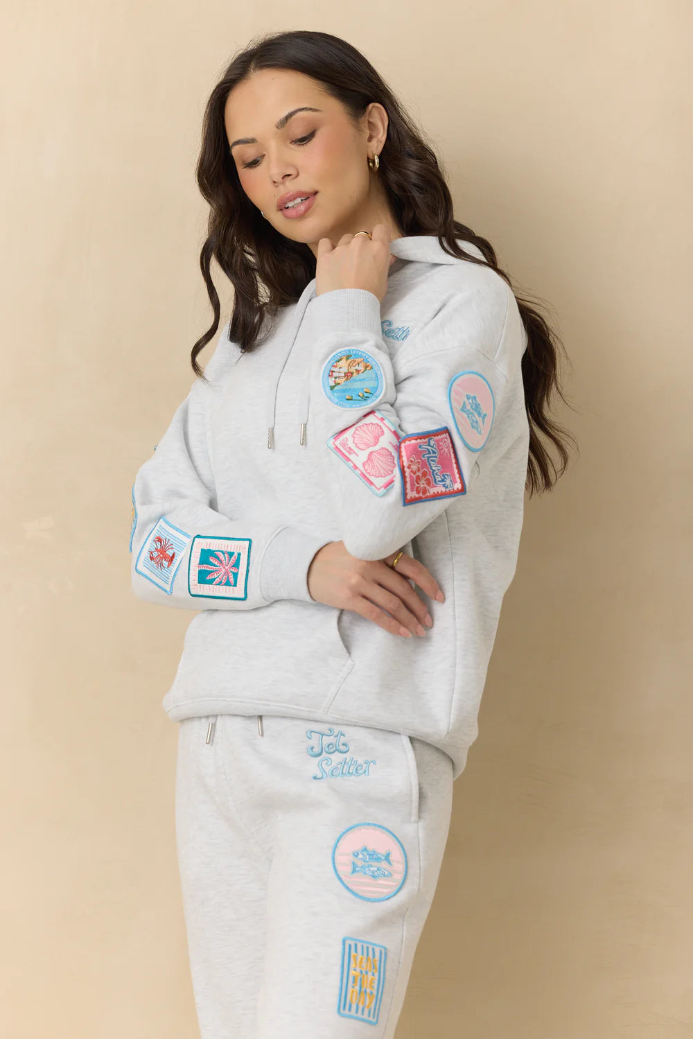 Woman wearing embroidered hoodie with patches on plain background