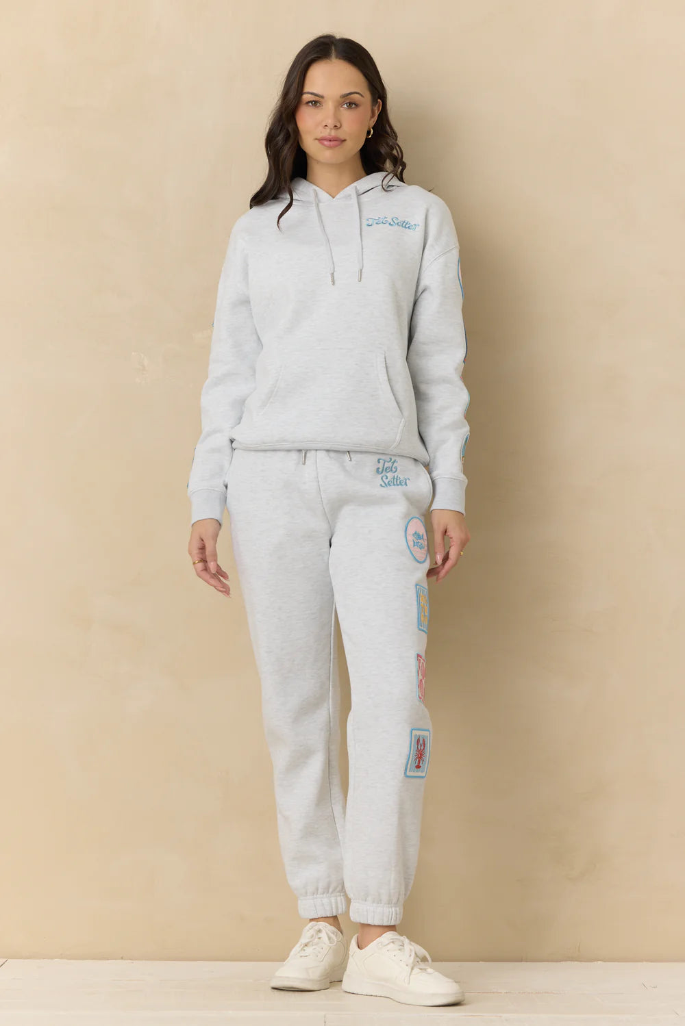 Woman wearing grey sweatshirt with embroidery on plain background