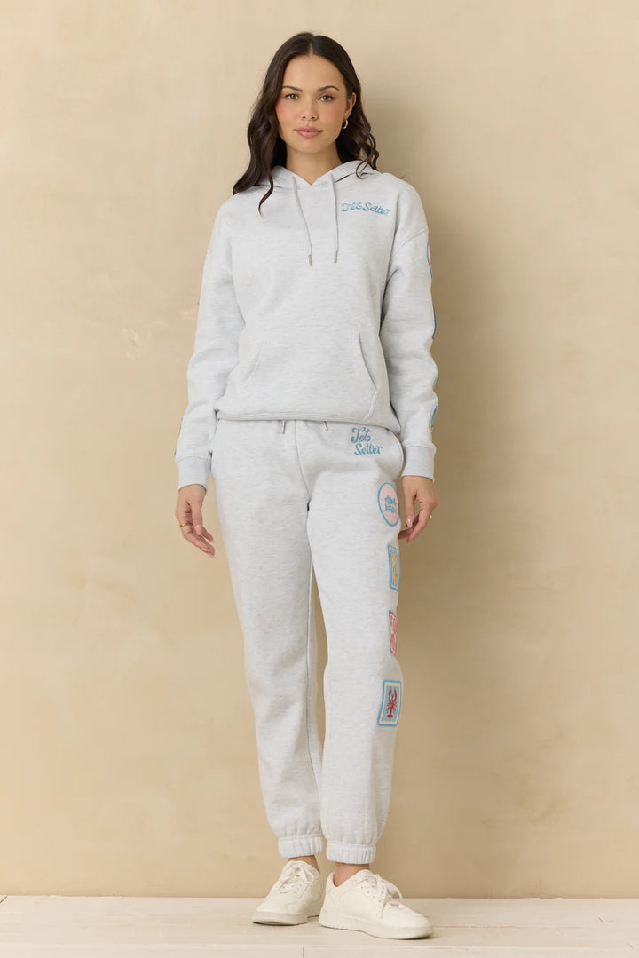 Woman wearing grey sweatshirt with embroidery on plain background