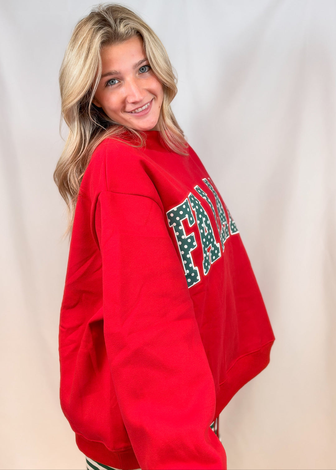 Woman shown from side view wearing red mock neck sweatshirt on plain background