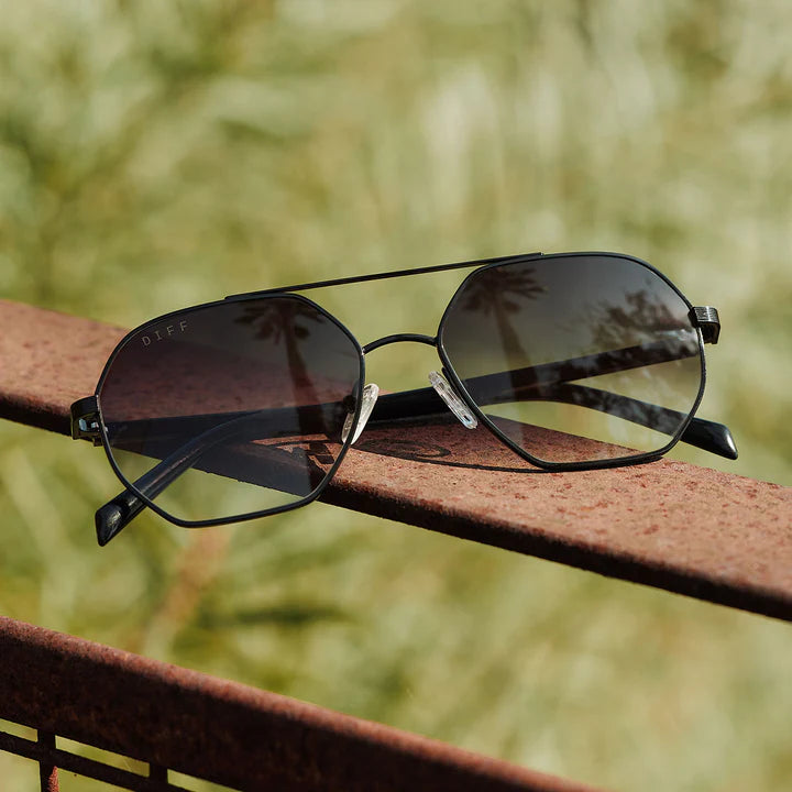 Sunglasses on a rusted metal surface with a blurred natural background