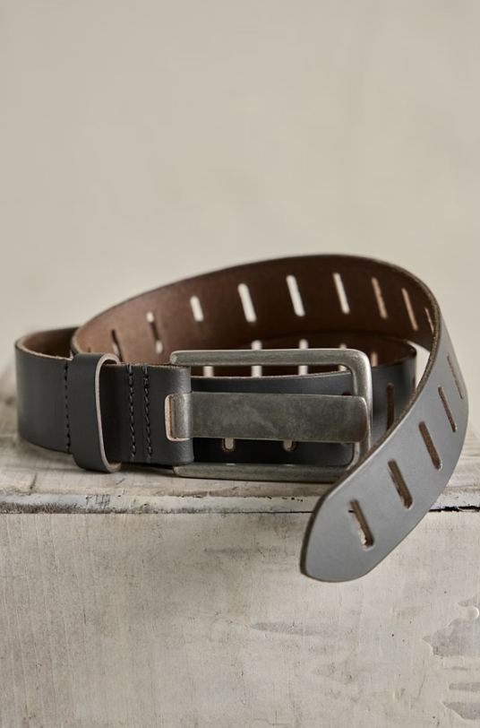 Dark grey slotted belt on cement block on beige background