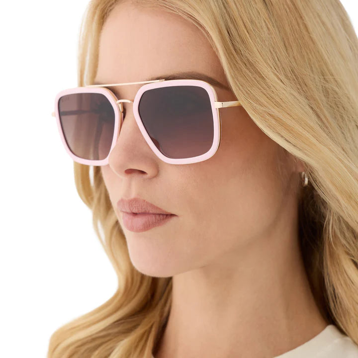 Woman wearing pink sunglasses with a neutral background