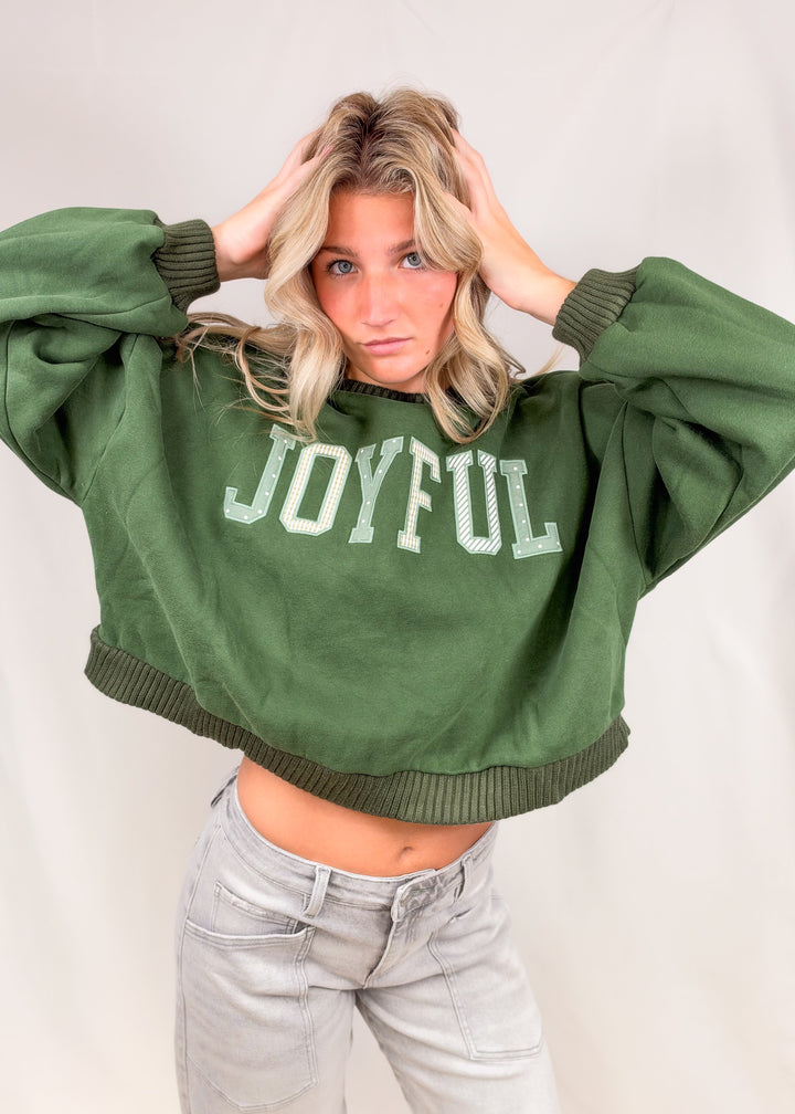 Woman wearing green mock neck sweatshirt with &