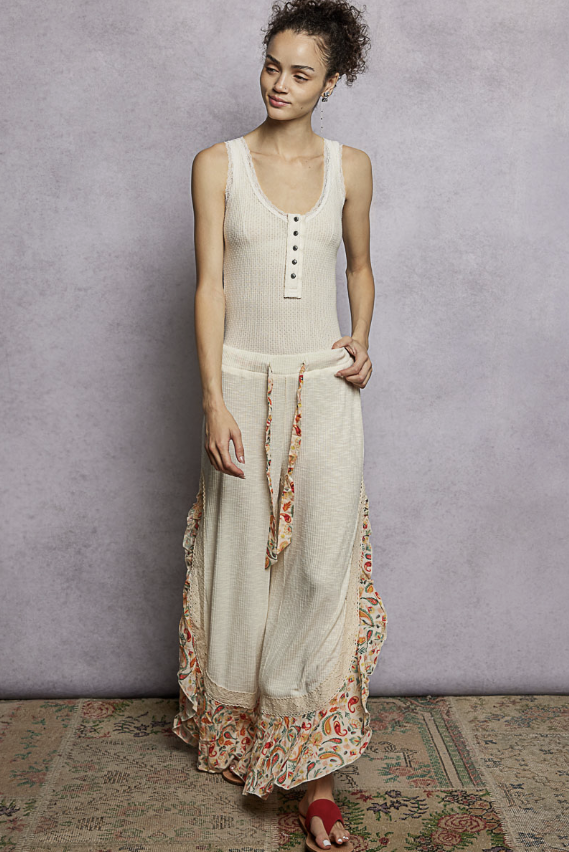 Woman wearing cream tank and pants on plain background
