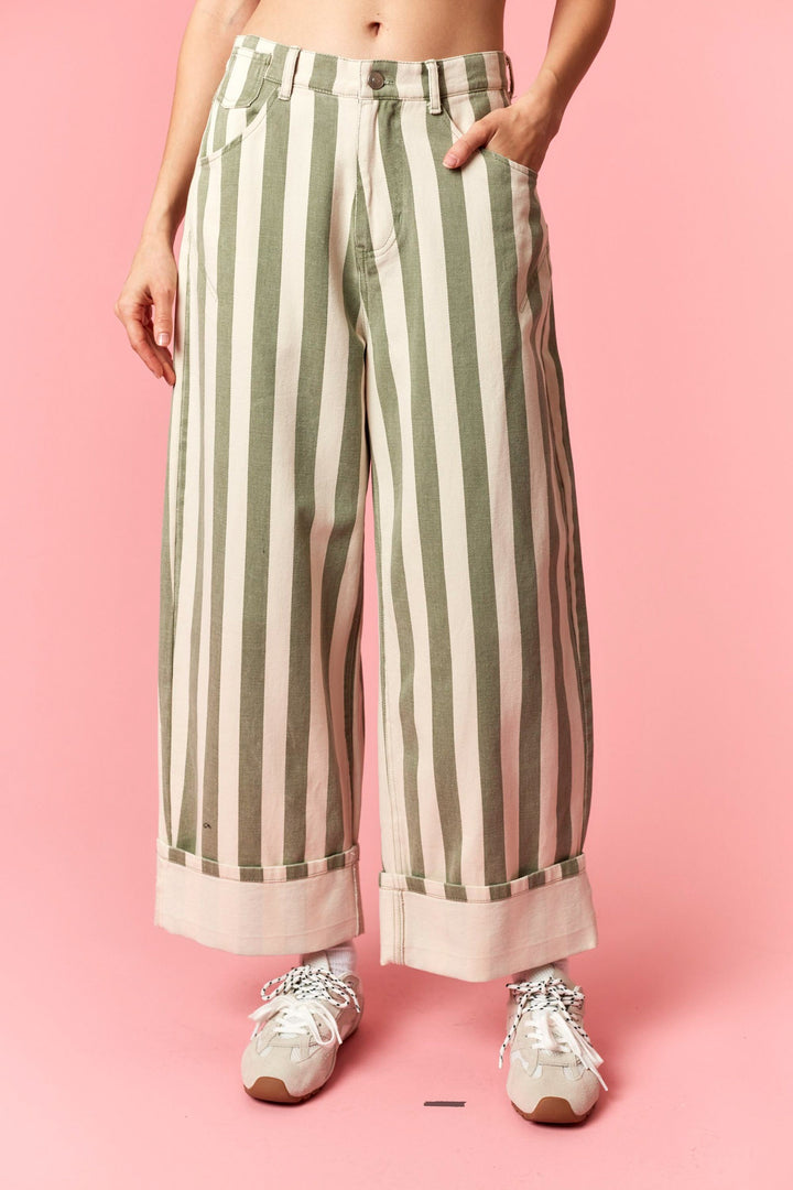 Person wearing green and white striped pants on a pink background