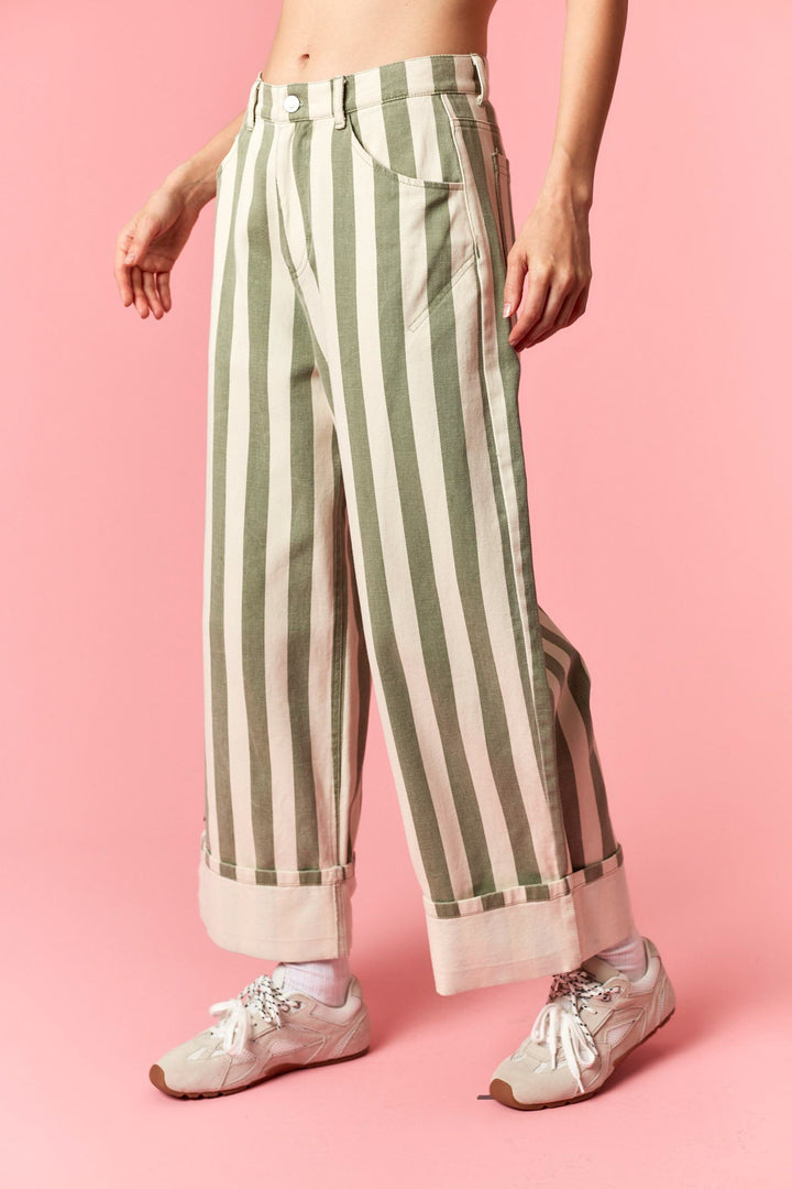 Person wearing green and white striped pants on a pink background