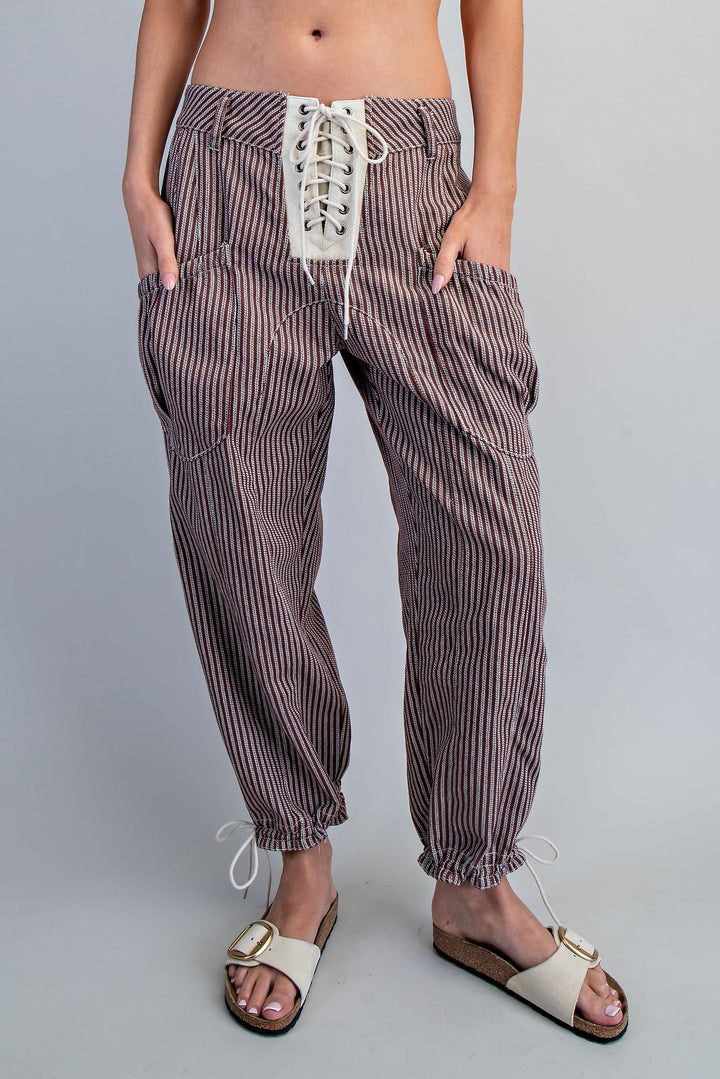 Striped pants with lace-up front worn by a person on a gray background