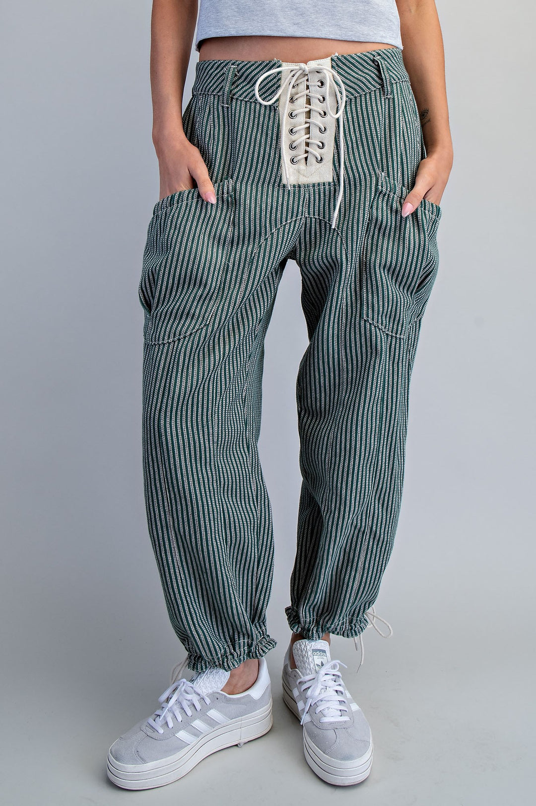 Person wearing green striped pants with lace-up front on a gray background
