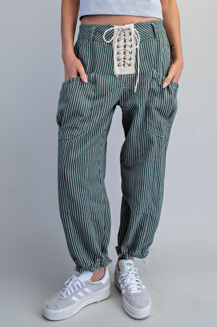 Person wearing green striped pants with lace-up front on a gray background